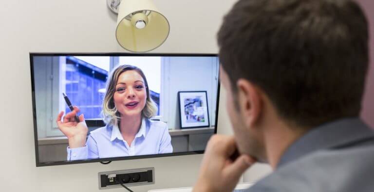 A man having a teleconference with a young blonde woman.