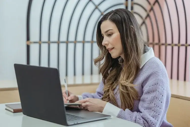 alt text: woman with laptop taking notes