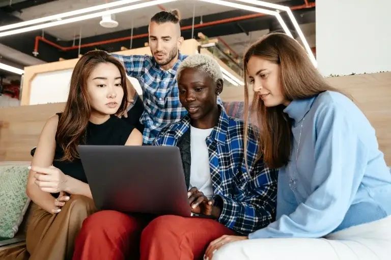 young people gathered around laptop